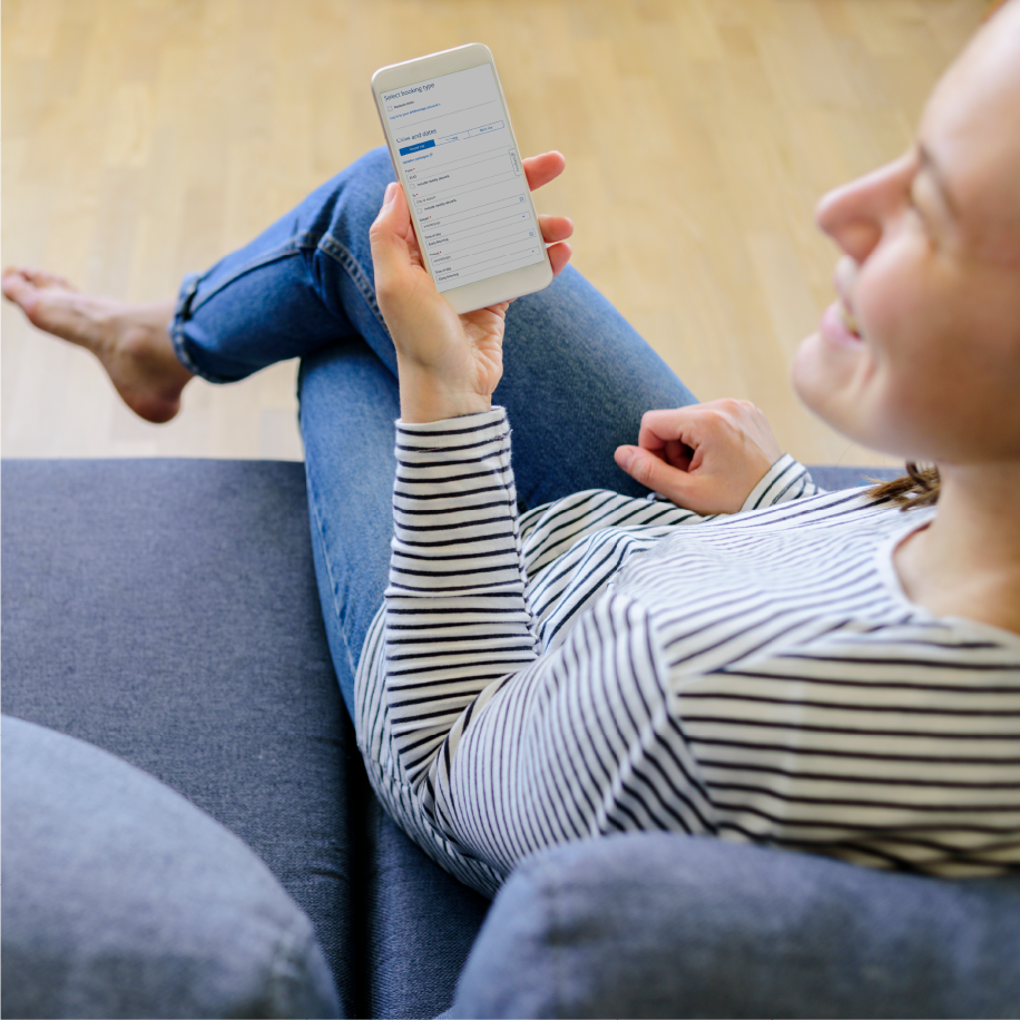 Woman relaxing on a couch using the American Airlines booking app on her phone