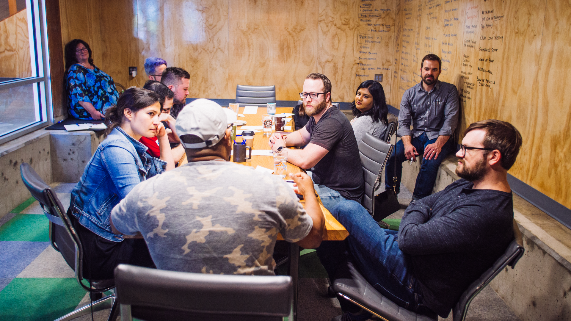 American Airlines workshop attendees seated around a table in a plywood-walled meeting room