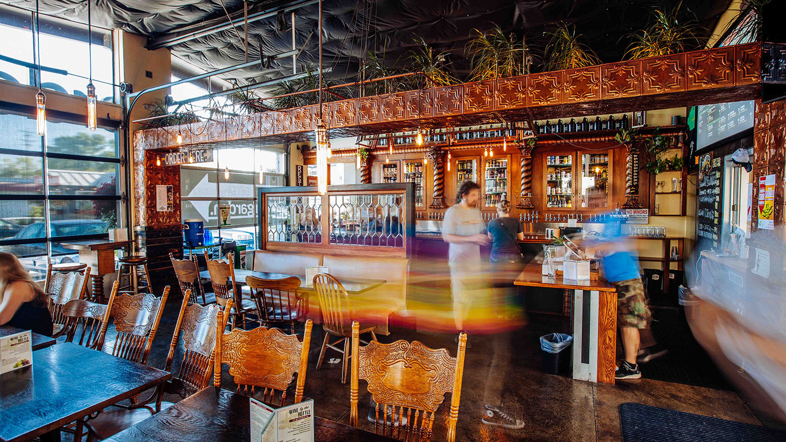 Interior of Beergarden with reclaimed-wood bar, pressed-tin ceiling and bartender pouring drinks