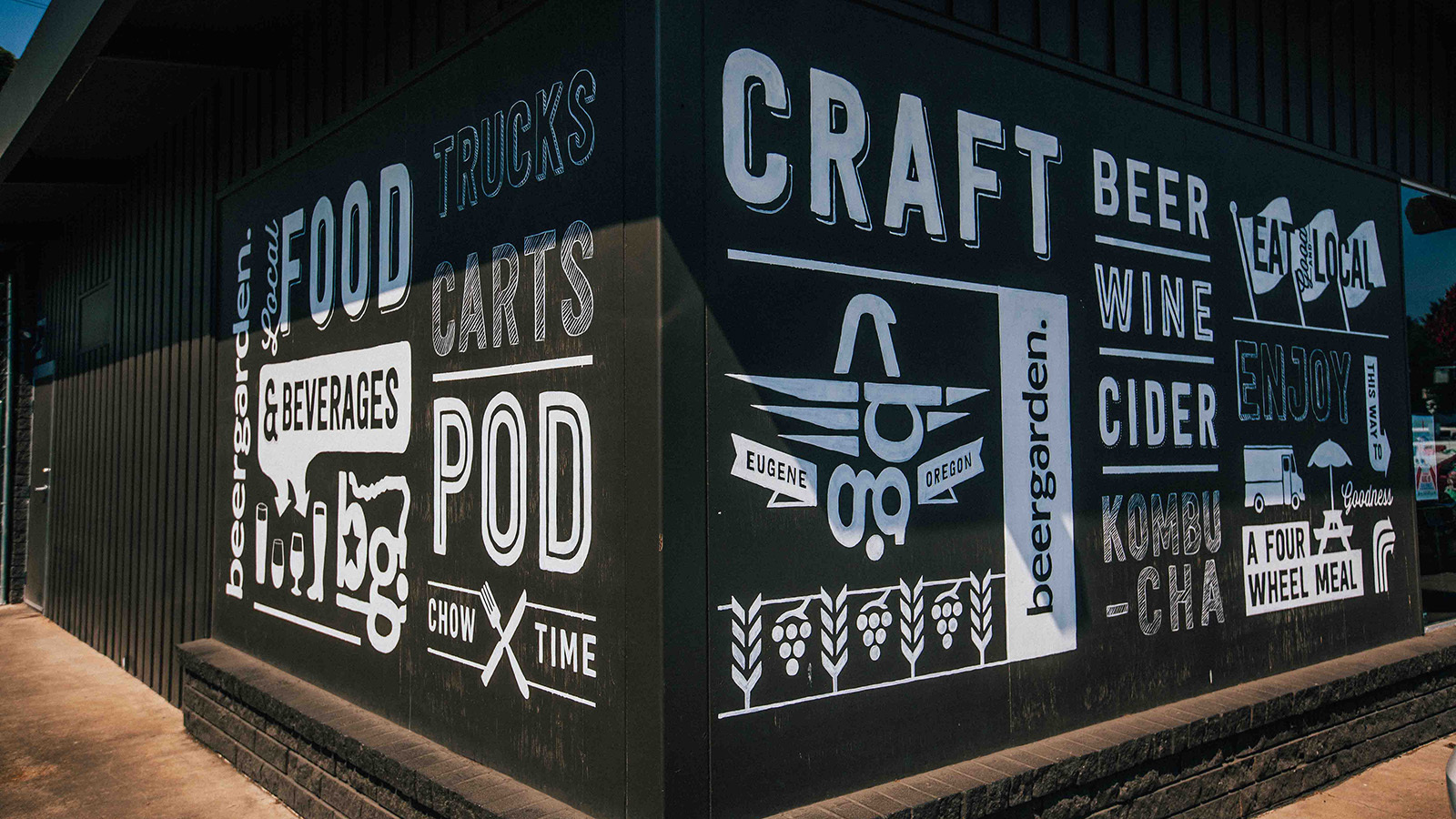 Black exterior wall with white painted Beergarden Eugene Oregon murals for food trucks, craft beer and cider