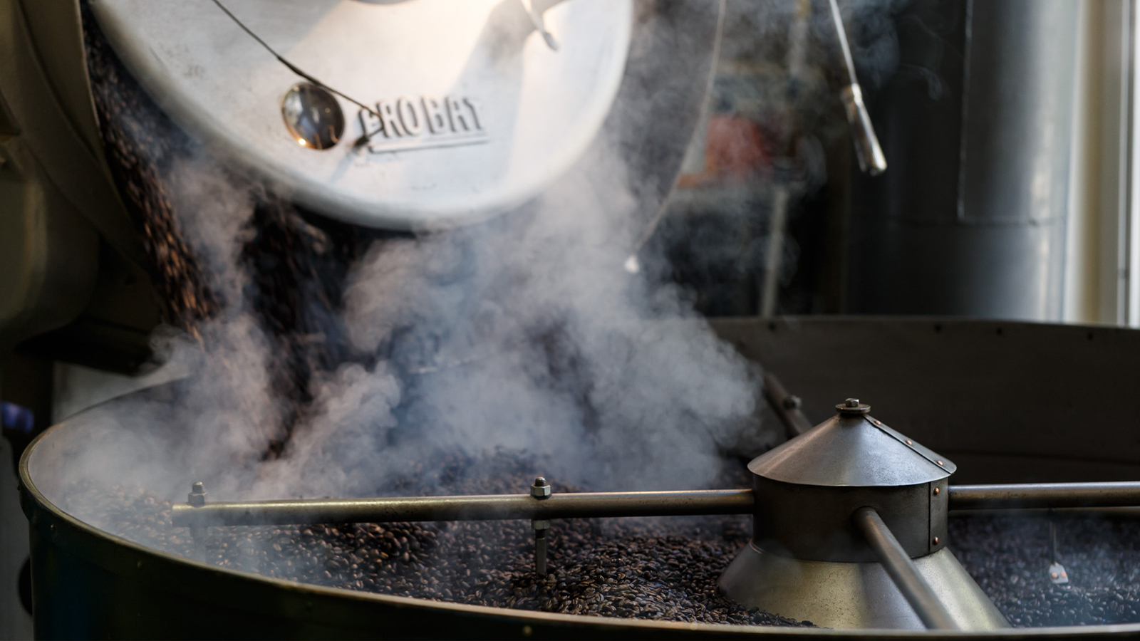 Coffee roasting drum venting steam over dark roasted beans at Cafe Mam