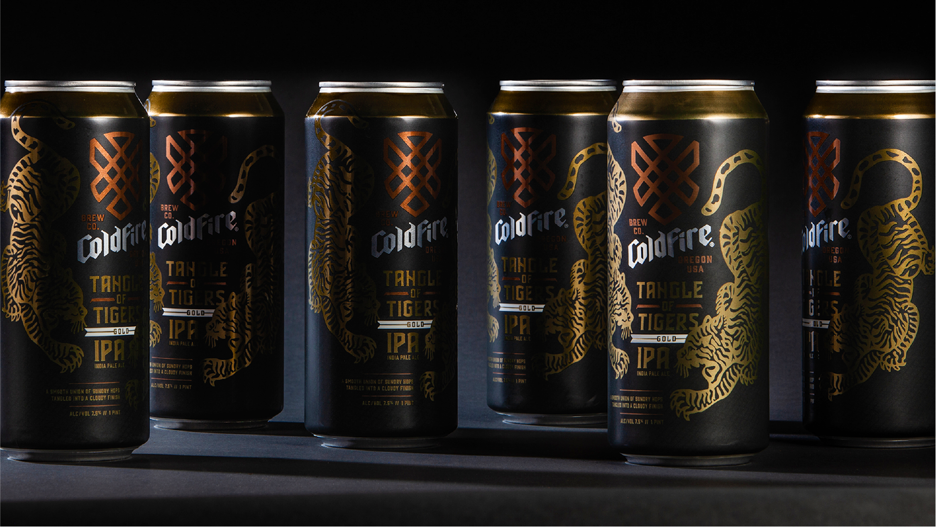 Row of black ColdFire Tangle of Tigers IPA cans with gold tiger artwork, lit dramatically
