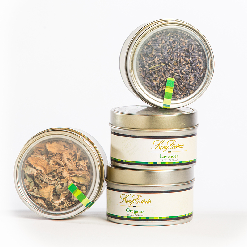 Stacked King Estate culinary tins of Lavender and Oregano with herbs visible inside lids