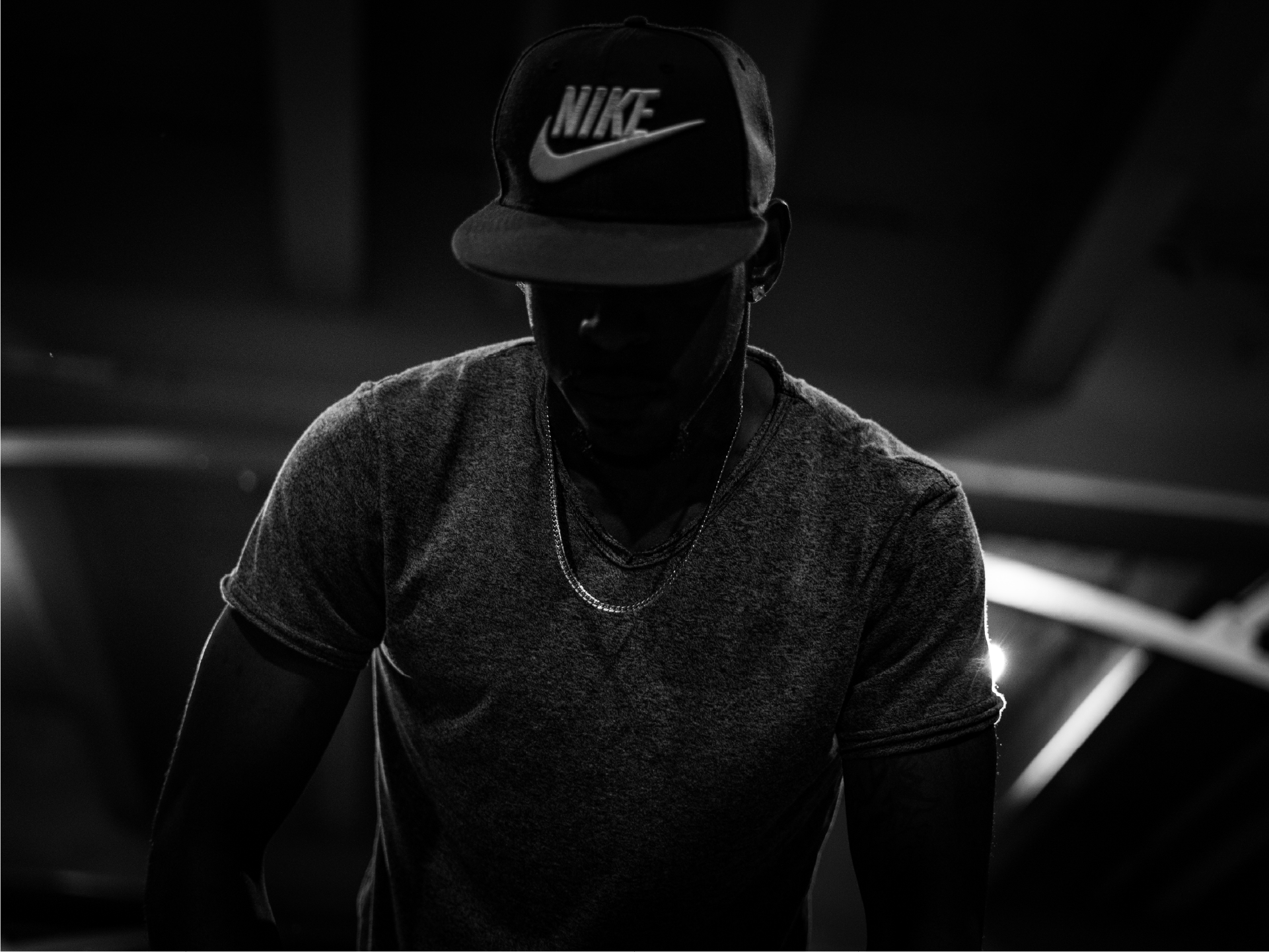Nike London: man in a black Nike cap and grey T-shirt in low light, black and white