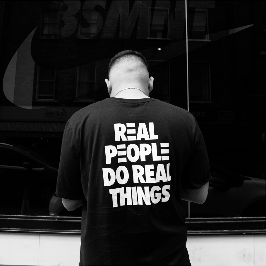 Nike London: man's back in a 'Real People Do Real Things' tee before a BSMNT Nike storefront