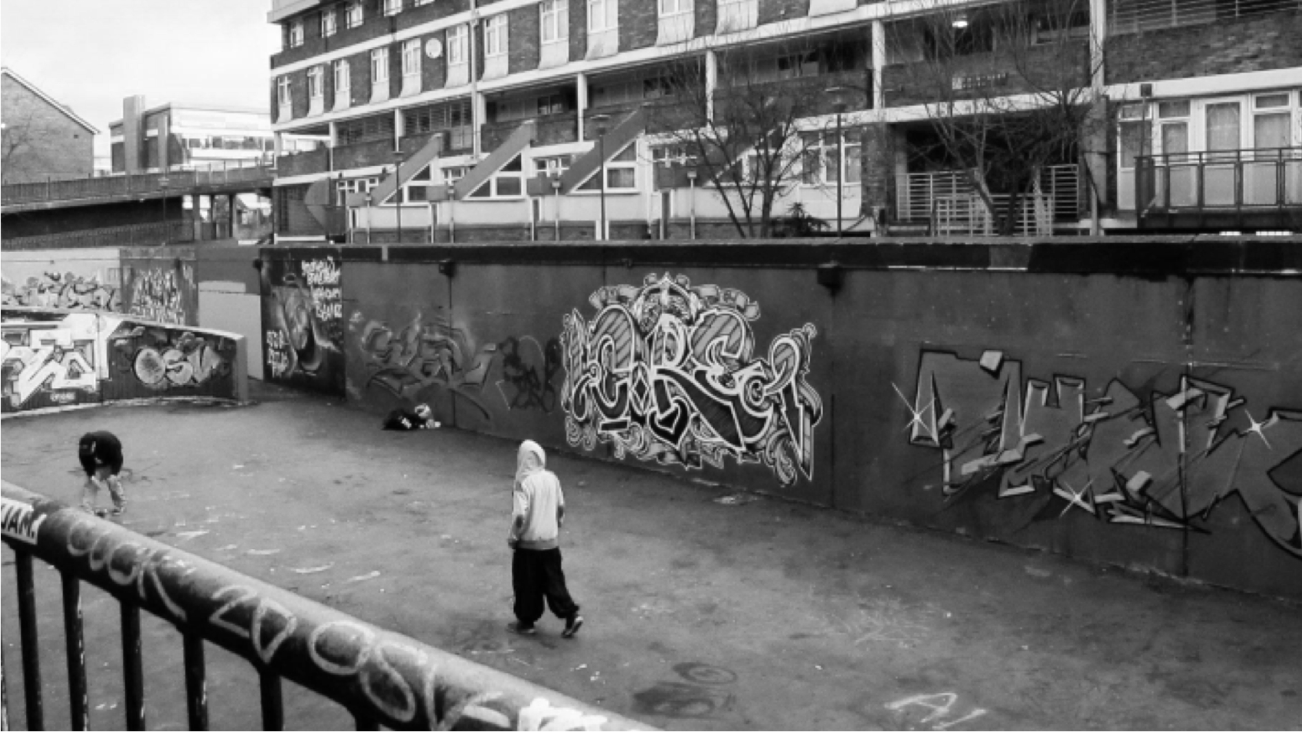 Person in a hood walks past a graffiti-covered wall by a London estate, Nike London case study
