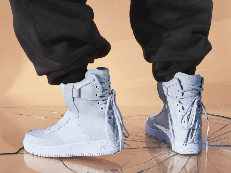 Person in black joggers wearing white Nike Air high-top sneakers standing on cracked glass, Nike London