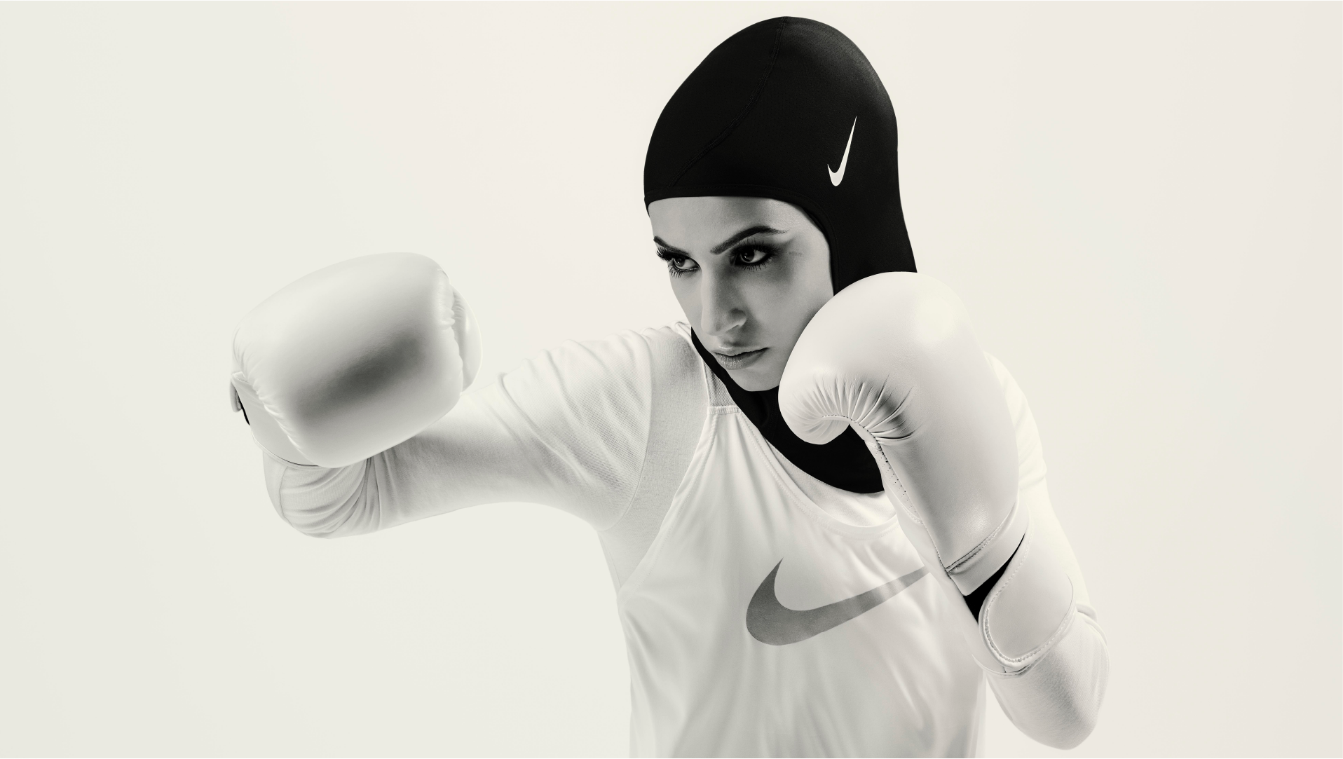 Nike London: woman boxing in a black Nike Pro Hijab and white top with boxing gloves raised