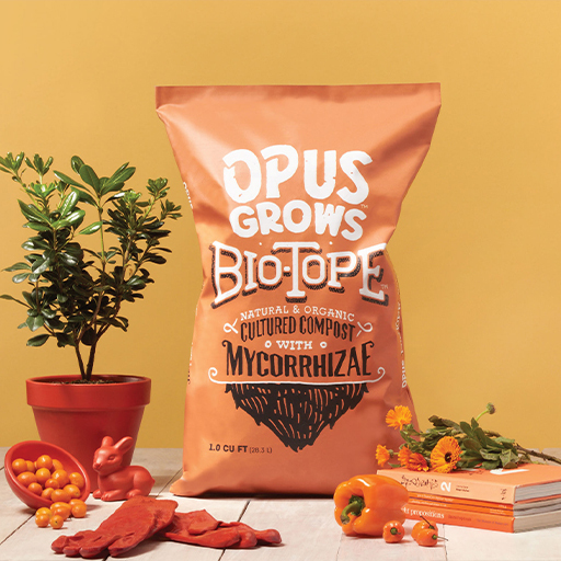 Orange Opus Grows Biotope Cultured Compost with Mycorrhizae bag beside potted plant and tools