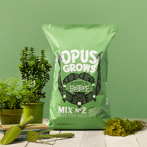 Opus Grows Bio-Tope Mix No.2 Nuts for Coco bag beside potted green plants and garden tools