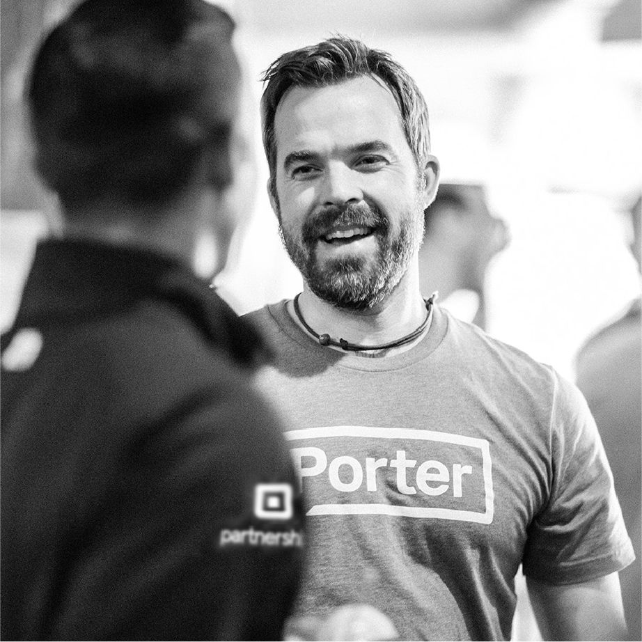 Smiling Porter team member in a Porter logo tee shaking hands at a Square partnership event