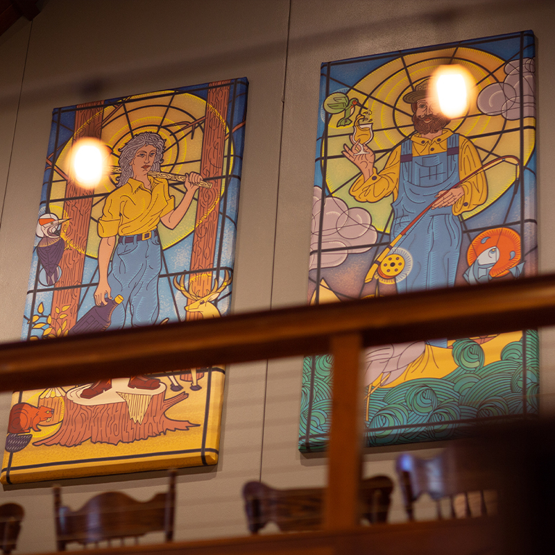 Two stained-glass murals of a logger and a fisherman mounted above the railing at Public House