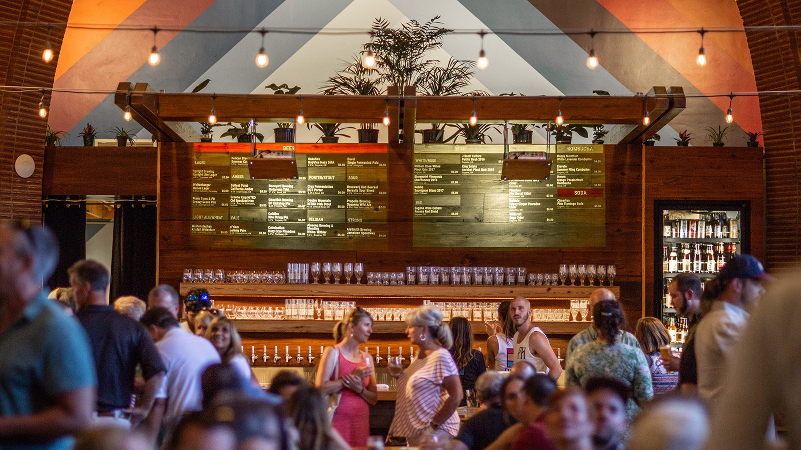 Public House food hall interior with chalkboard menus, full bar and a busy crowd under string lights