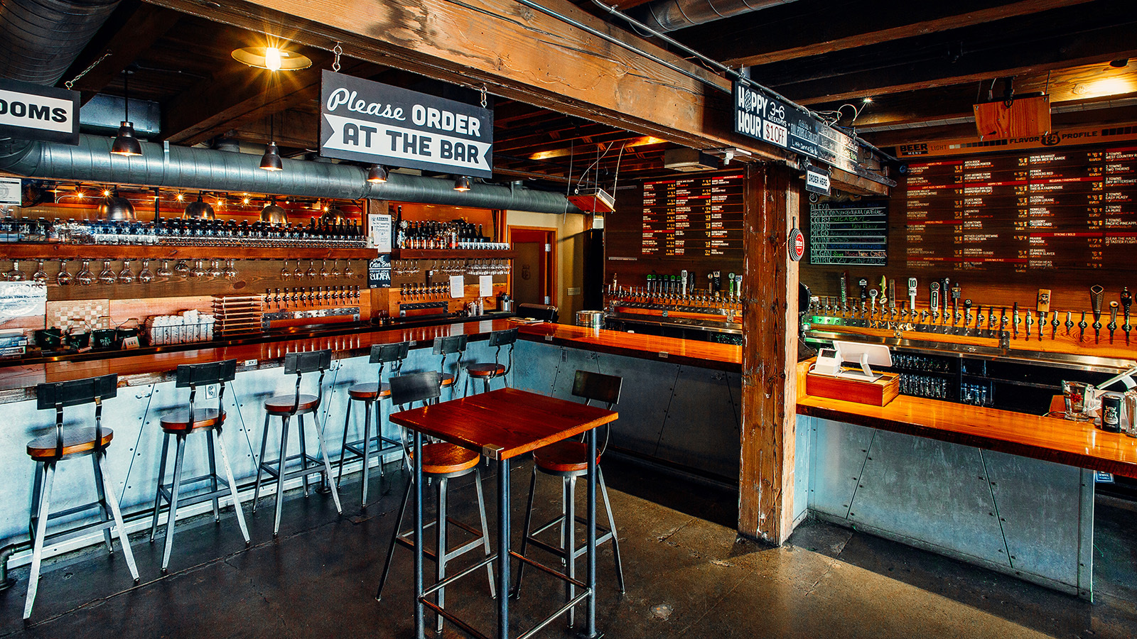 Tap and Growler food hall bar interior with stools, beer taps and 'Please order at the bar' sign