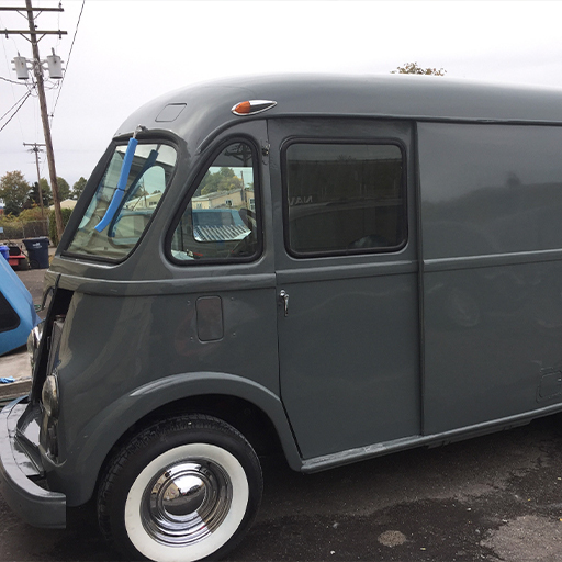 Grey vintage step van with whitewall tires mid-restoration in a lot, WSECU Let's Co build
