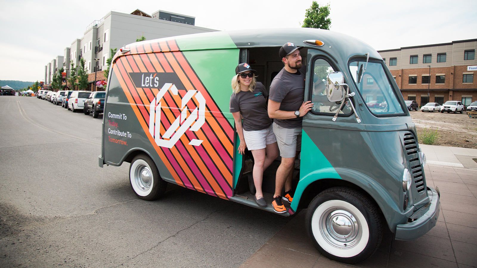 Couple stand in a Let's Co branded vintage van parked on a street, WSECU campaign