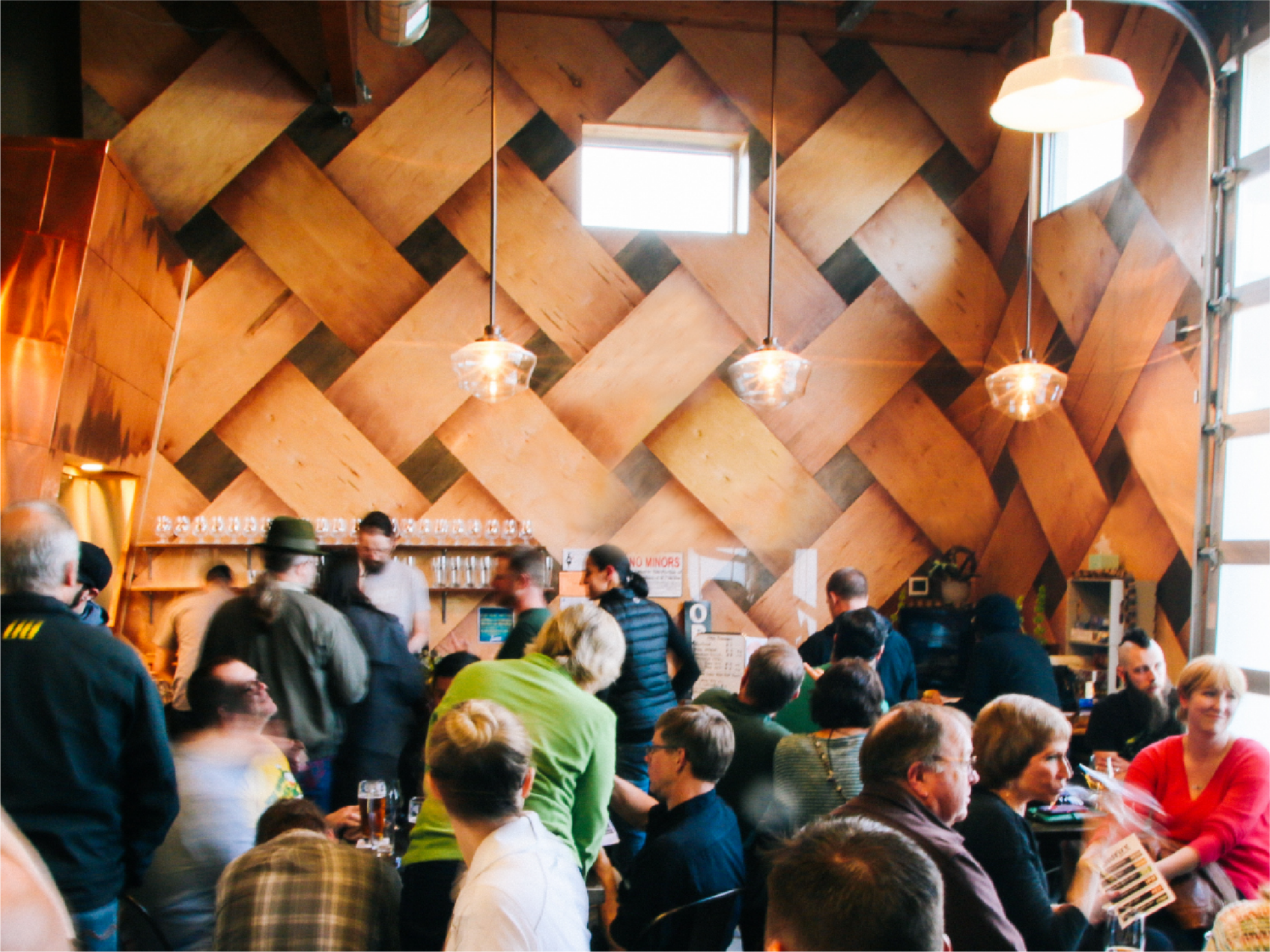 Busy ColdFire taproom crowd beneath a striking diagonal woven-plywood feature wall and pendant lights
