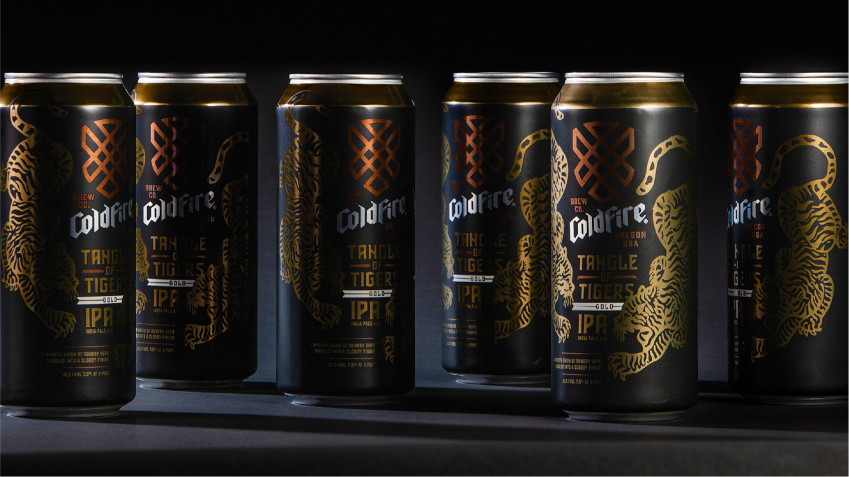 Row of black ColdFire Tangle of Tigers IPA cans with gold tiger artwork, lit dramatically