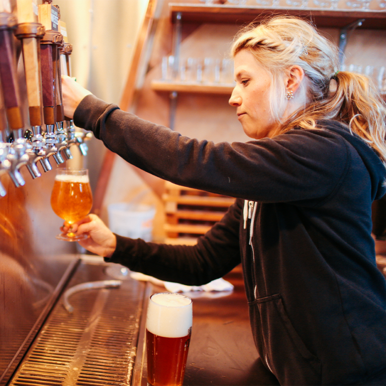 Bartender pouring a glass of ColdFire beer from the tap row in the taproom