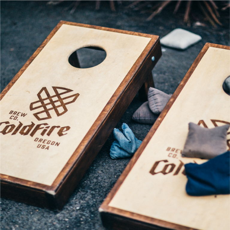 Wooden cornhole boards branded with the ColdFire Brewing logo and tossed beanbags
