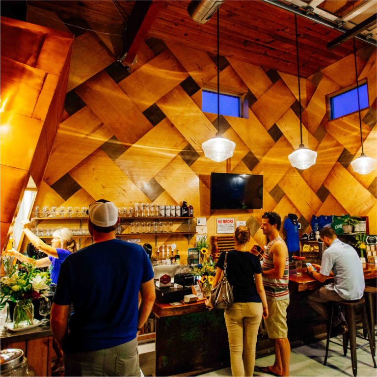 Patrons ordering at the bar inside ColdFire Brewing's taproom with woven wood ceiling