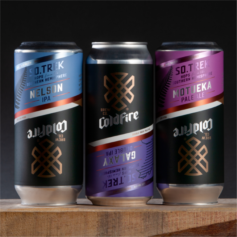 Three ColdFire So.Trek cans: Nelson IPA, Galaxy double IPA, and Motueka pale ale on a wood surface