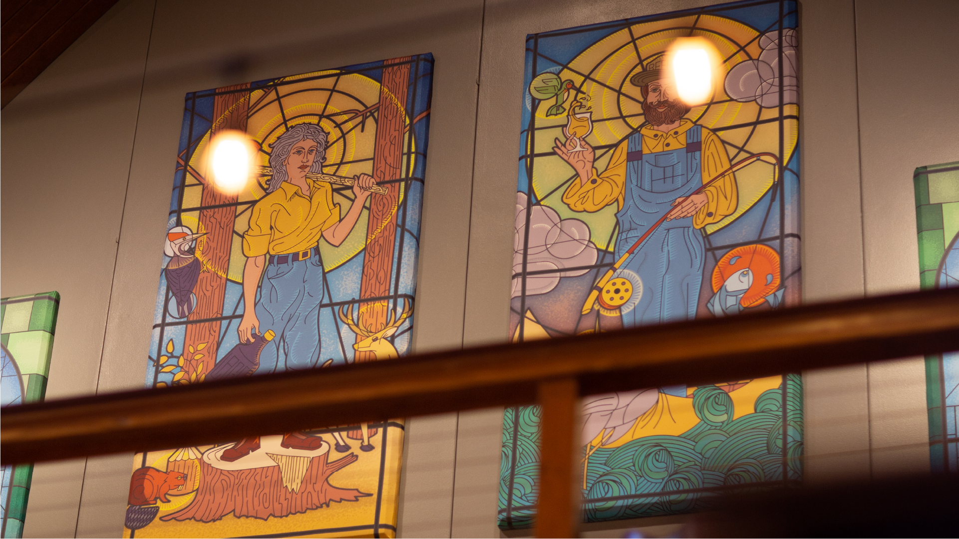 Two stained glass windows depicting a woman and a bearded man in workwear among trees