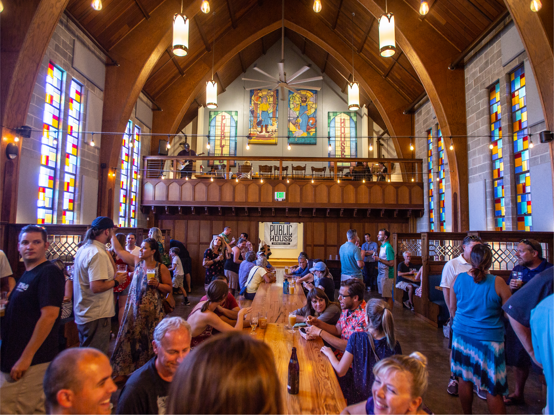 Crowd inside Public House, a converted church with stained glass, arches and a long table
