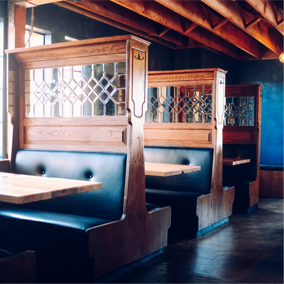 Restaurant booths with oak dividers and leaded diamond-pane glass over green leather seating