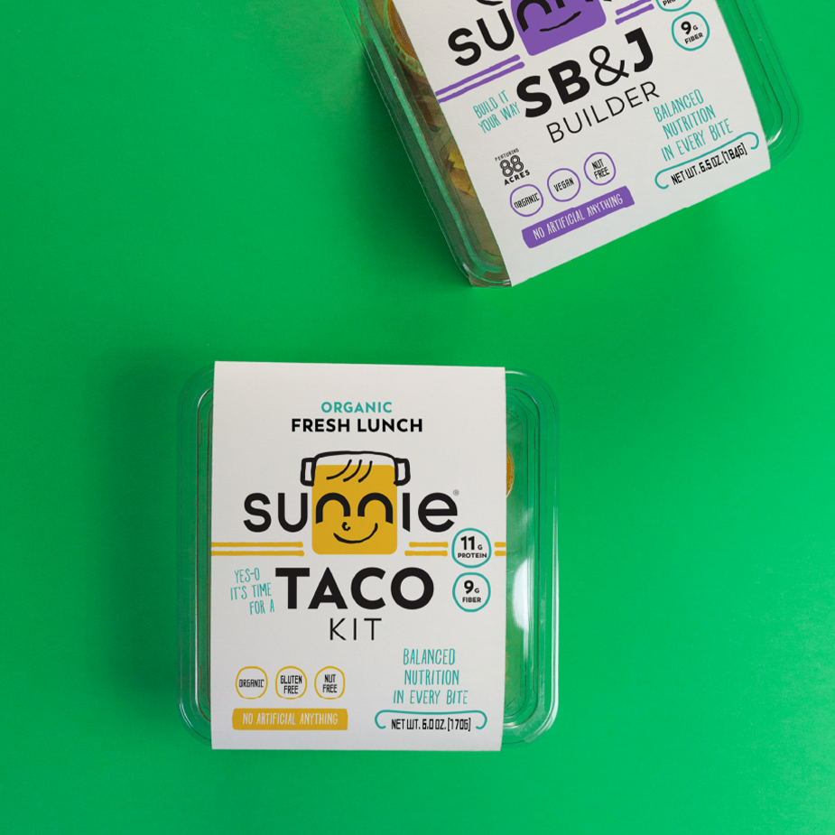Sunnie Taco Kit and SB&J Builder Fresh Lunch packs on a green background