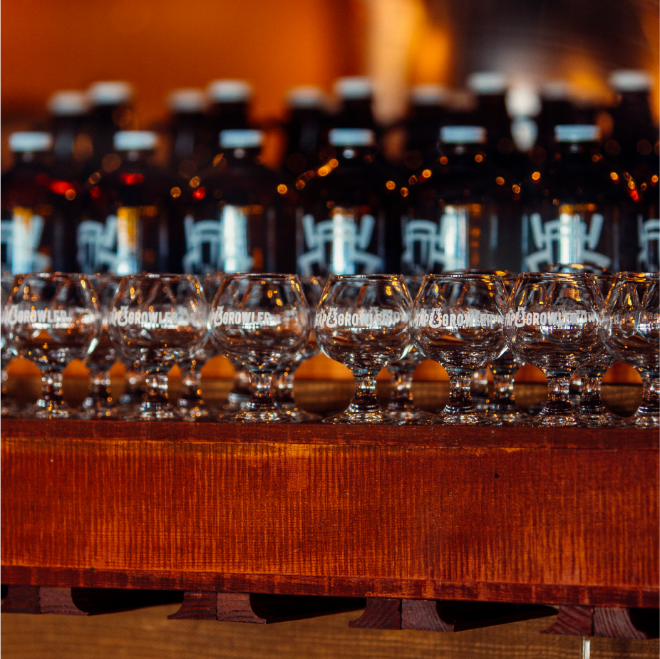 Row of small Borowler tasting glasses lined up on a wood counter at a taproom