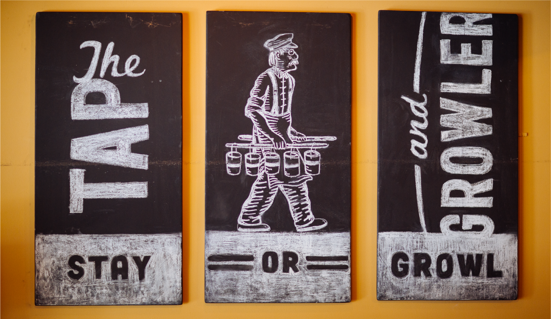 Three chalkboard signs reading 'The Tap and Growler', 'Stay or Growl' with an etched server figure