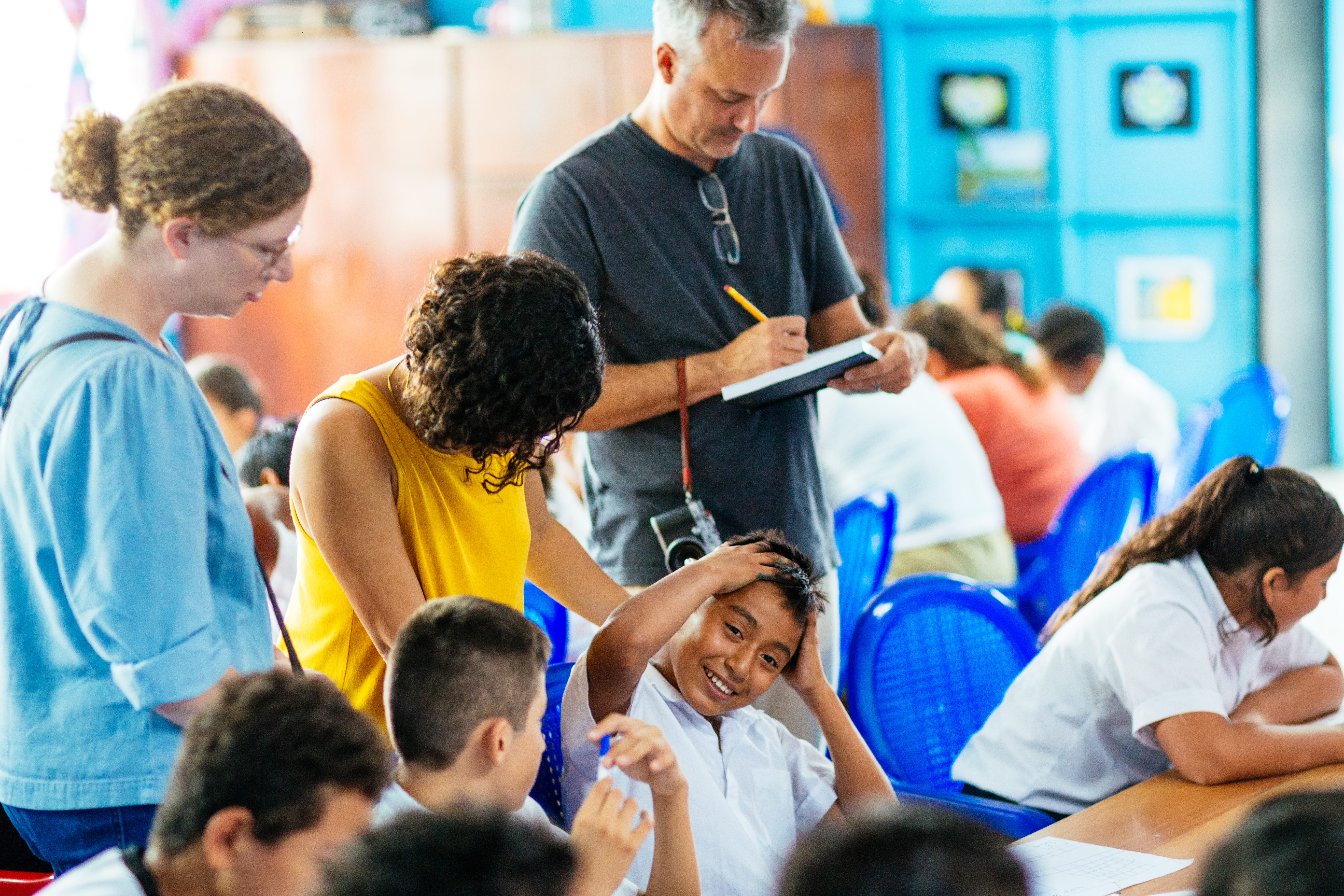 Man taking notes among schoolchildren during a design research session, El Salvador
