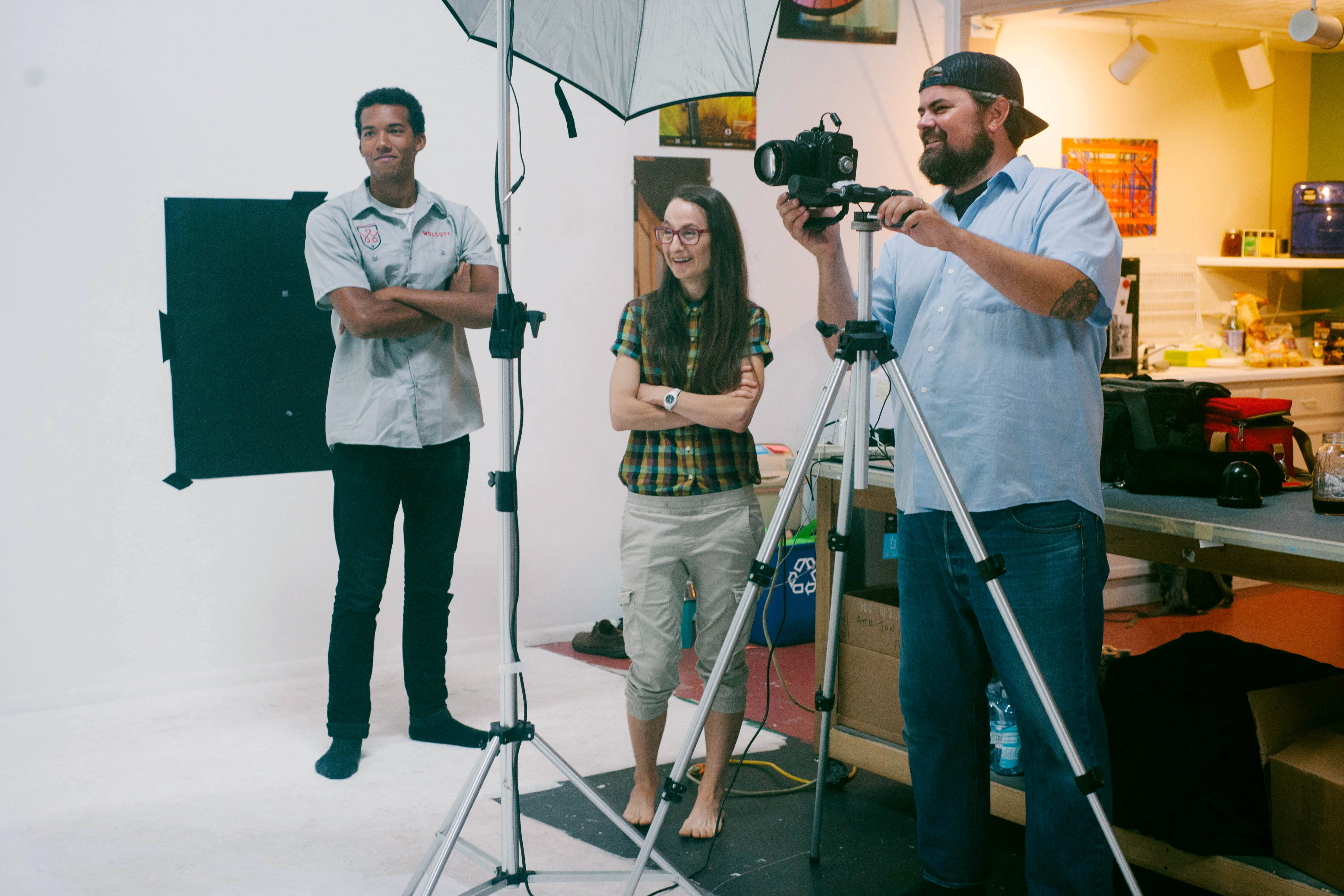 Photographer behind a tripod camera with two colleagues on a studio photo shoot set