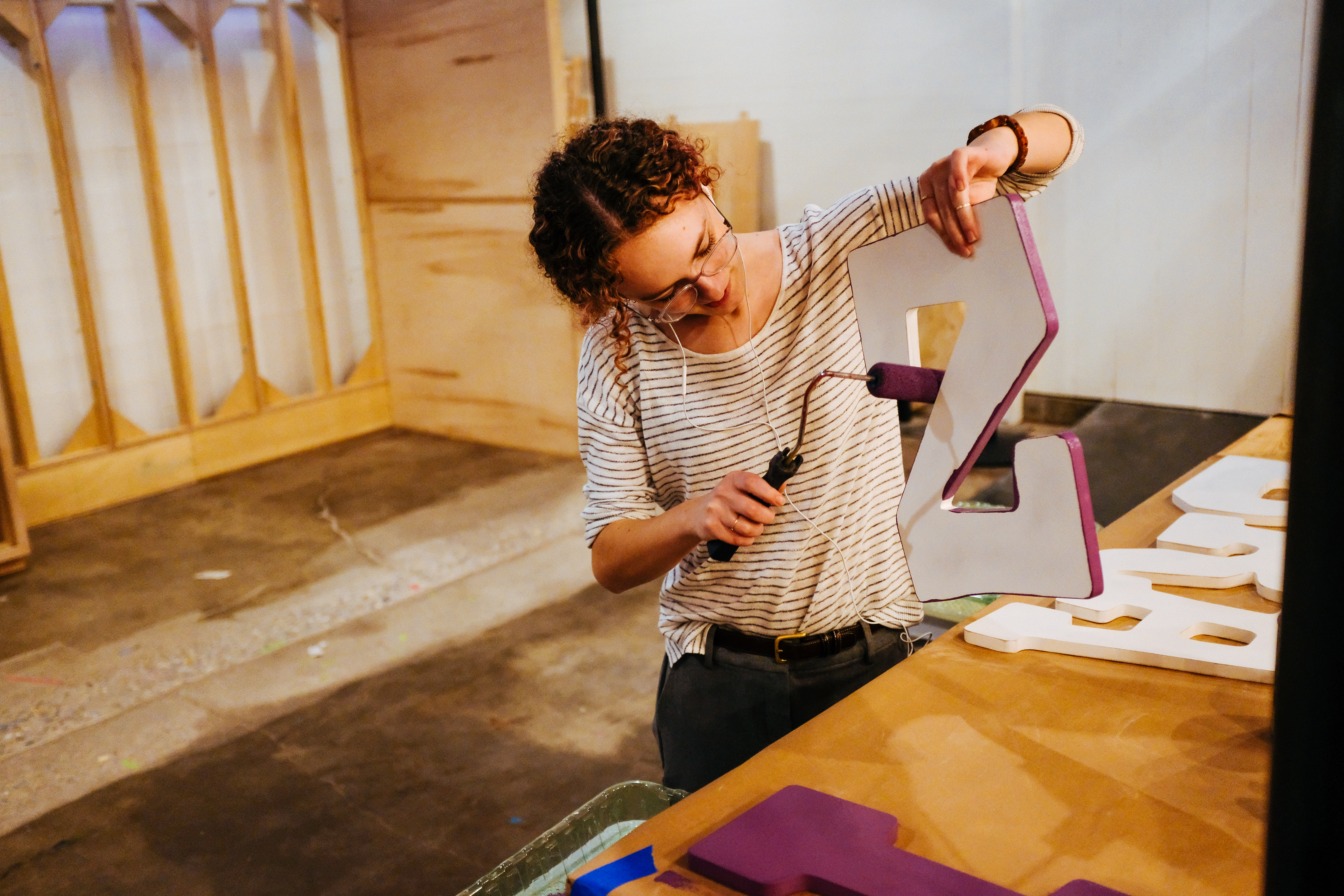 Woman using a tool to assemble large dimensional letters in the Drawn fabrication workshop