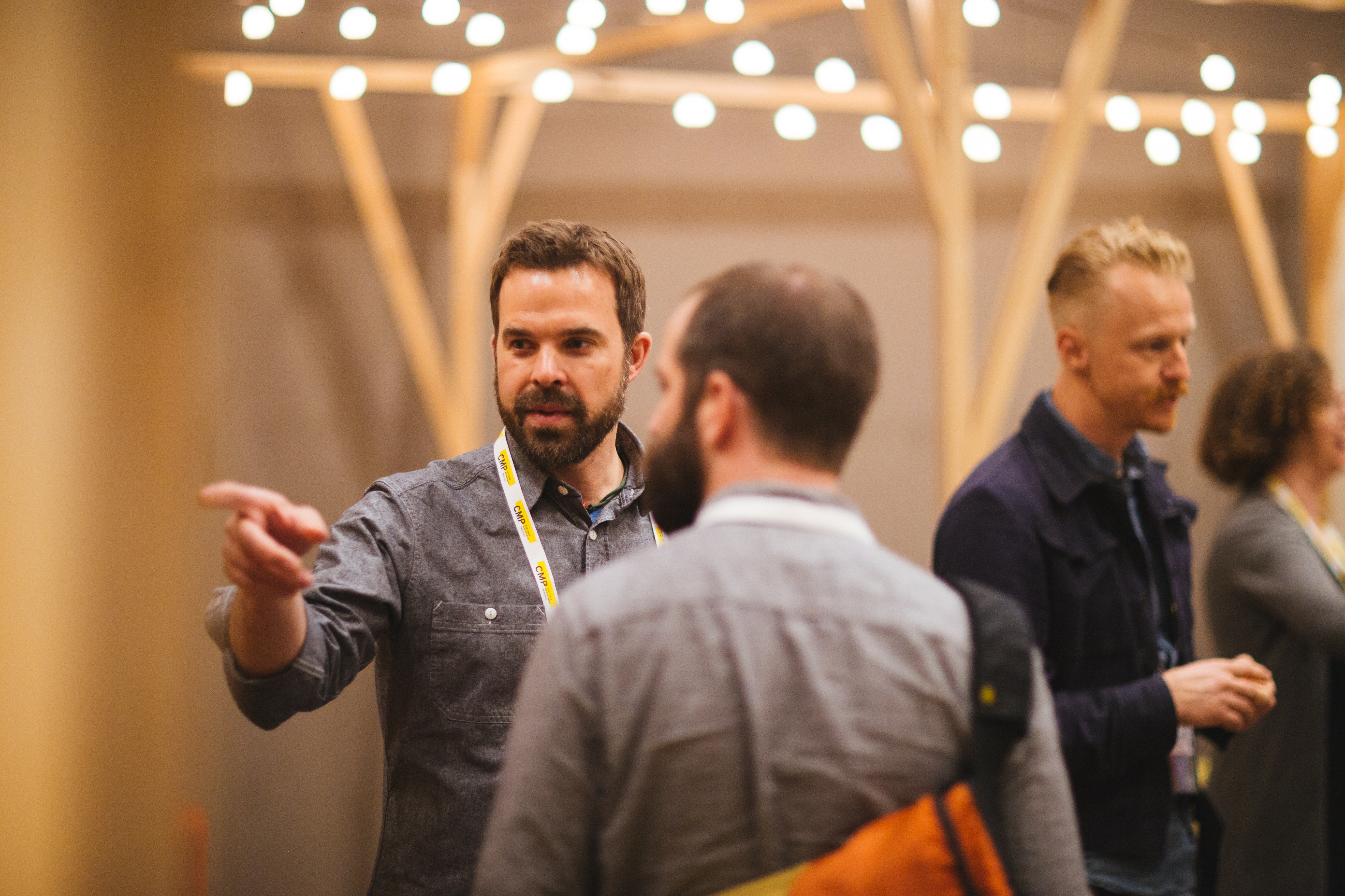 Drawn designer gesturing while talking with colleagues under string lights at a design event