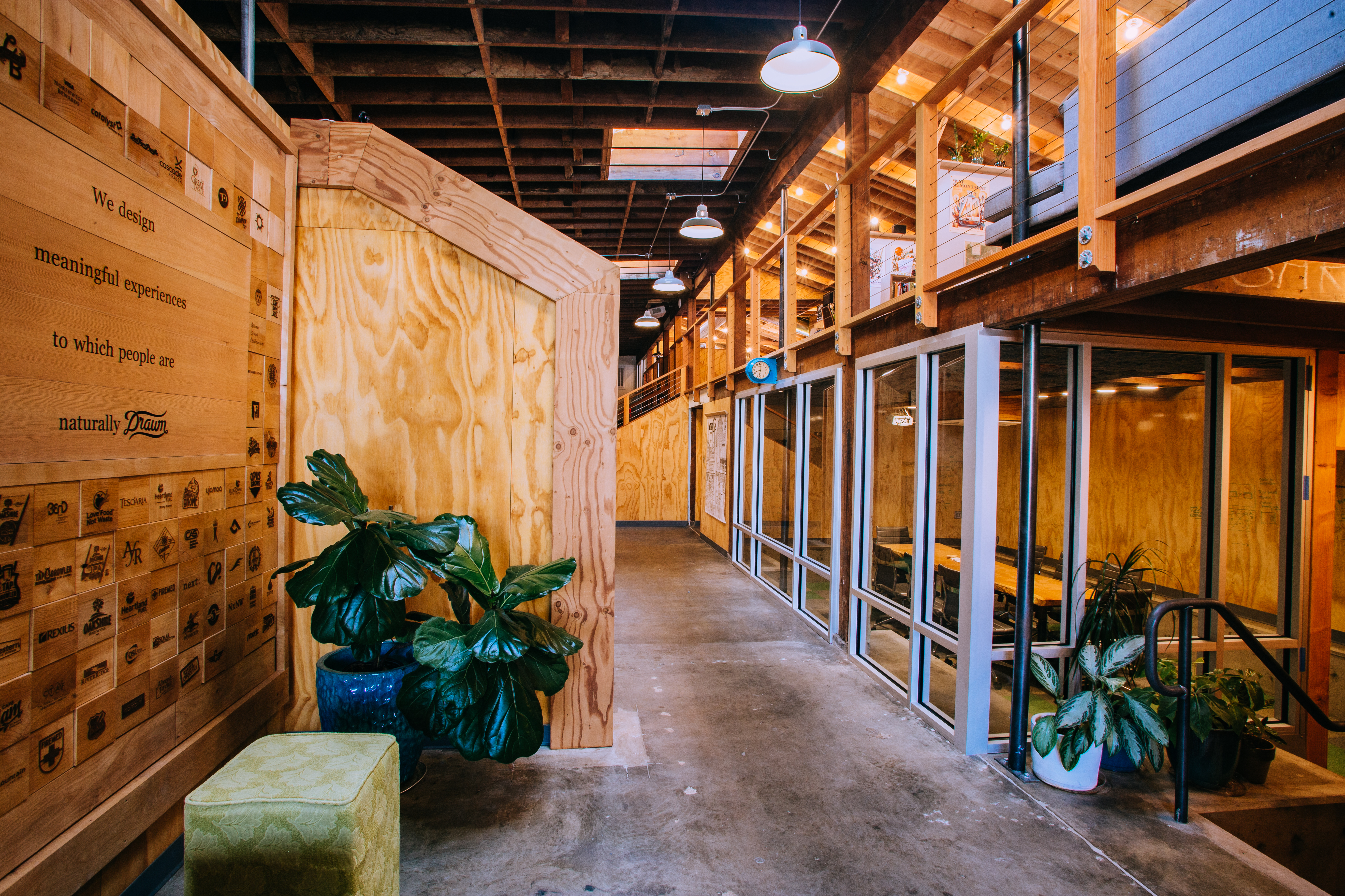 Interior hallway of the Drawn studio with plywood walls, plants and a We design meaningful experiences sign