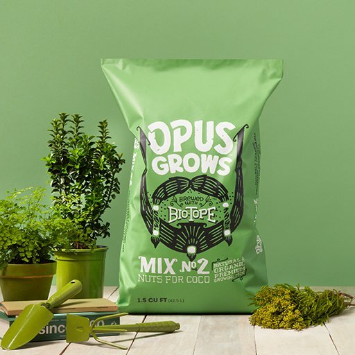 Opus Grows Biotope Mix No. 2 green soil bag beside potted plants and garden trowels