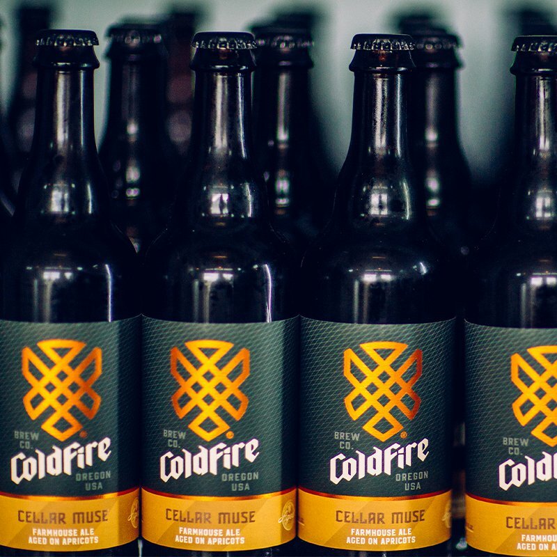 Rows of ColdFire Brewing Cellar Muse farmhouse ale bottles aged on apricots