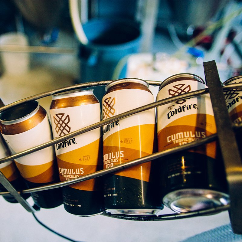 ColdFire Brewing Cumulus Tropicalus cans in a carrier inside the brewery