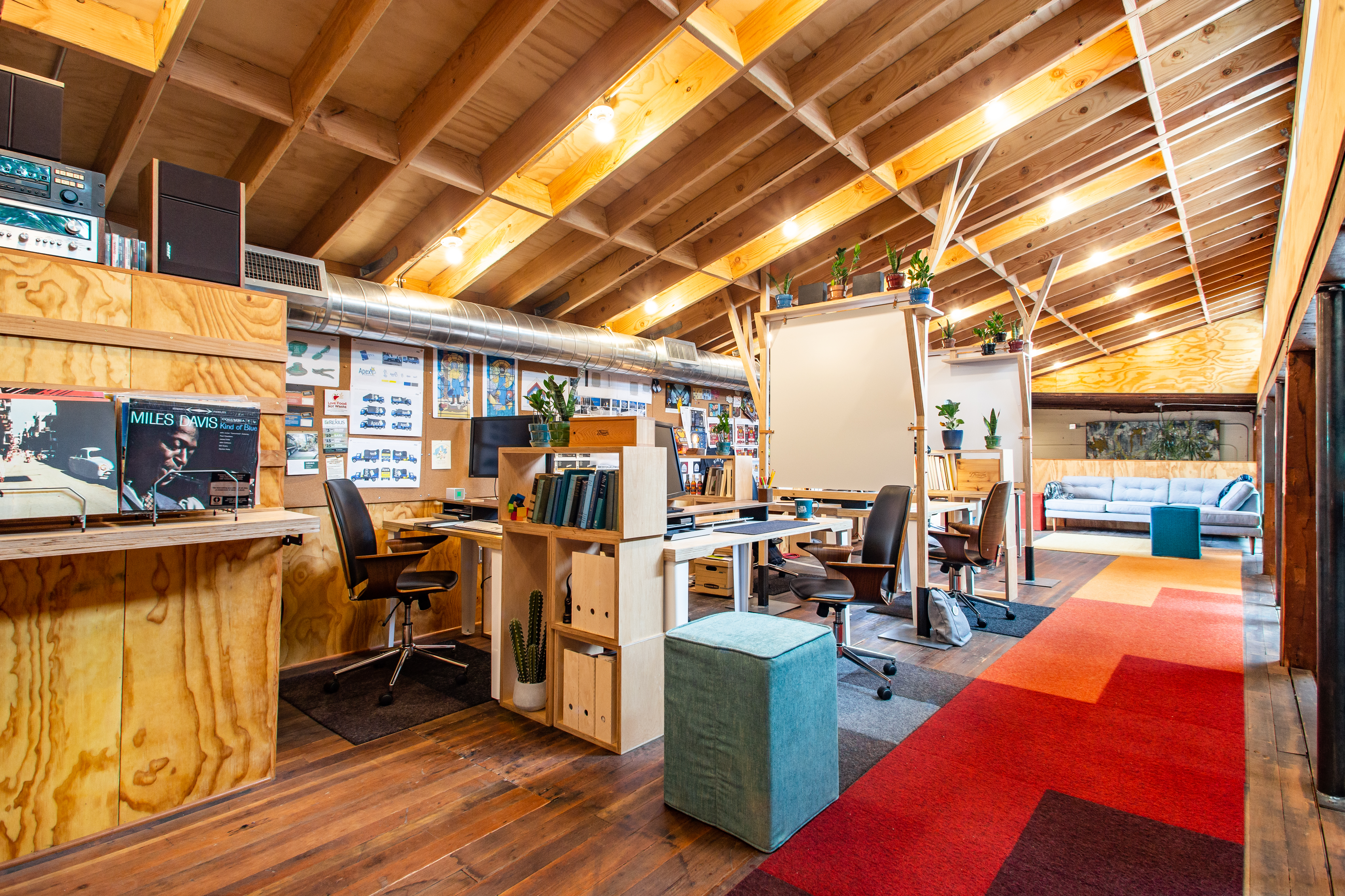 Drawn's open studio loft with wood-beam ceiling, standing desks, records on display and a colorful rug