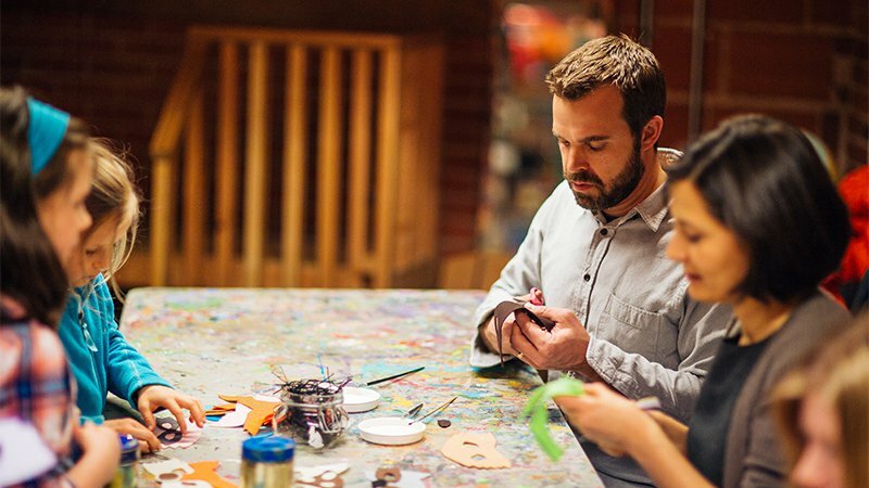 Man and others making holiday crafts at a paint-splattered Drawn studio table