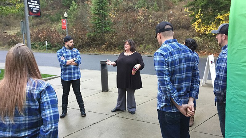 Woman leading an outdoor discussion with a group in matching blue plaid shirts at a WSECU event