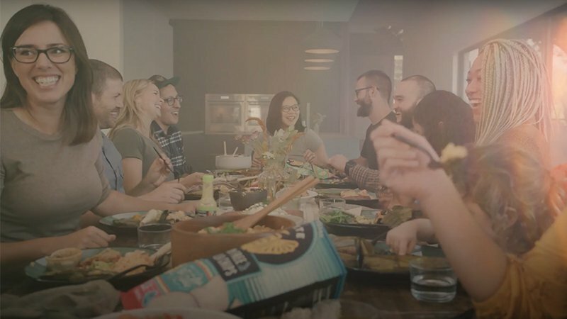 Siete family and friends laughing around a shared dining table full of food