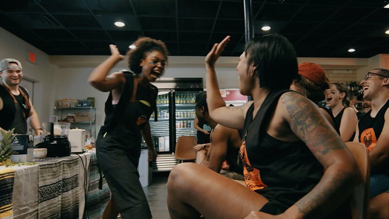 Siete team members laughing and high-fiving during a workout in their headquarters