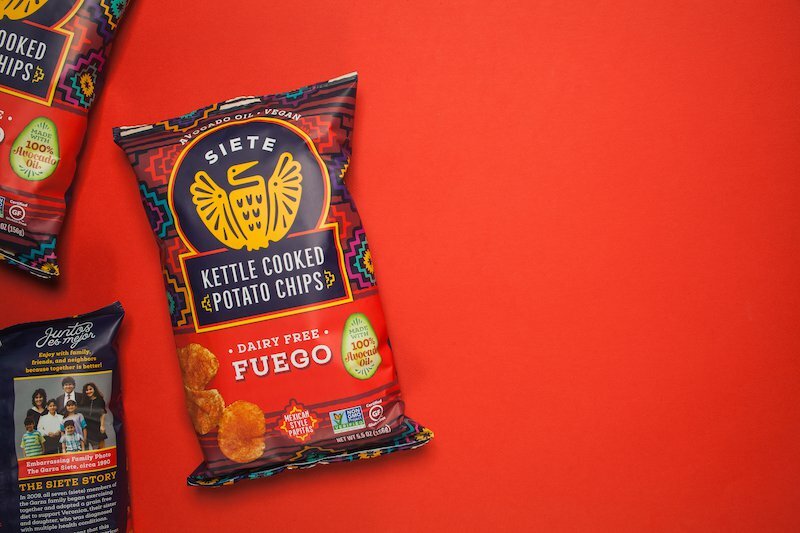 Siete Fuego Kettle Cooked Potato Chips bag on a red background beside other Siete packs