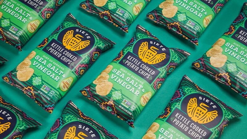 Siete Sea Salt & Vinegar Kettle Cooked Potato Chips bags arranged on a green background
