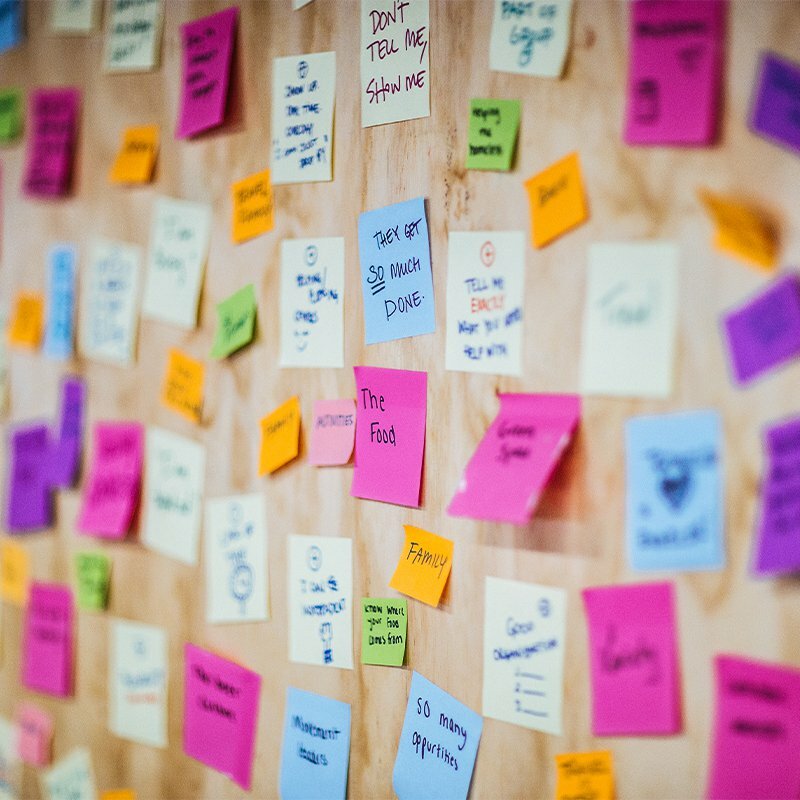 Wall covered in colorful sticky notes from a brand audit, reading phrases like 'Don't tell me, show me' and 'The food'