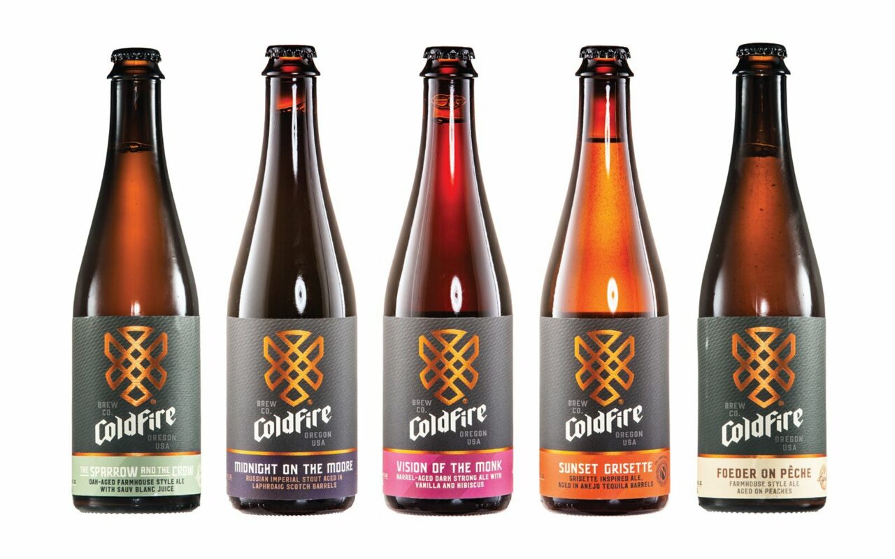 Five ColdFire Brewing barrel-aged farmhouse ale bottles with patterned labels lined up on white