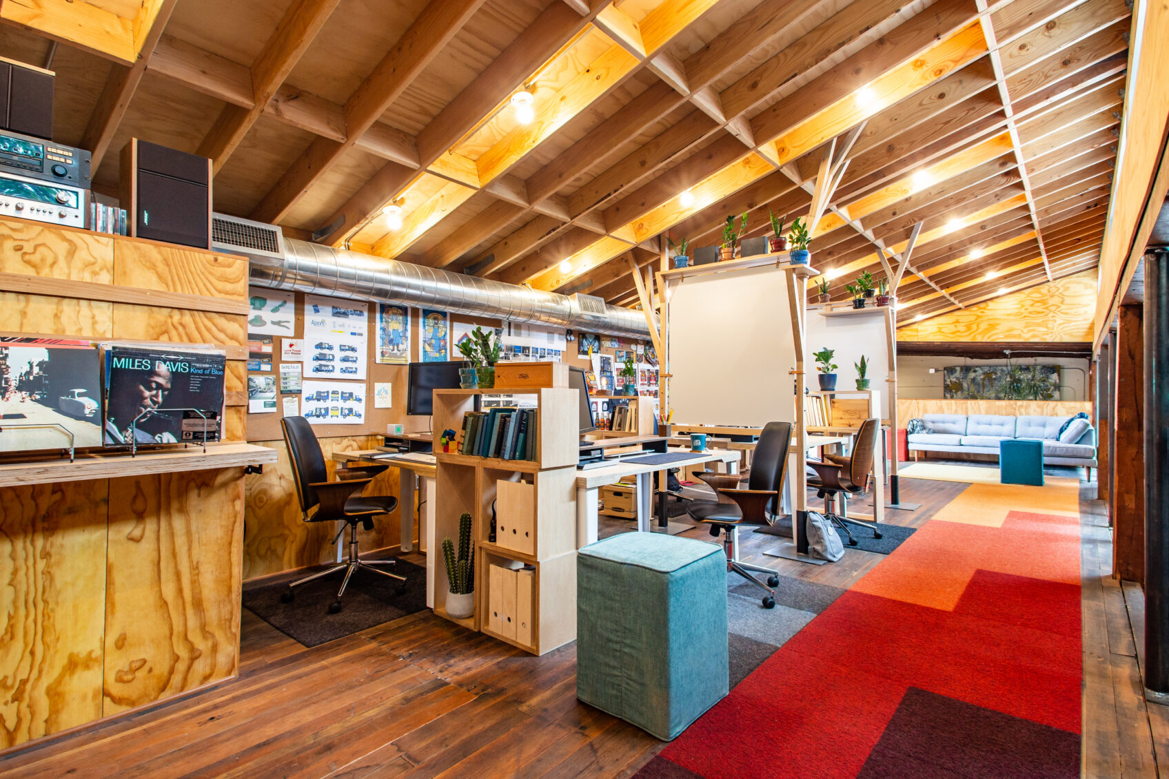 Drawn's open studio loft with wood-beam ceiling, standing desks, records on display and a colorful rug